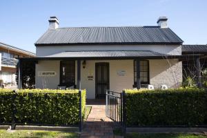 una pequeña casa blanca con techo negro en Centralpoint Motel, en Wagga Wagga