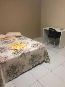 a bedroom with a bed with a floral bedspread and a desk at Pousada São Lucas in Salgueiro