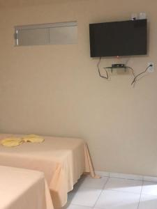 a room with two beds and a tv on the wall at Pousada São Lucas in Salgueiro