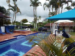 蒙特內格羅的住宿－Finca El Recreo - El Descanso，一座拥有棕榈树和蓝伞的游泳池