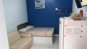 Kleines Zimmer mit einem Bett und einem Kühlschrank. in der Unterkunft Chalé do Tio Beto - Caraguatatuba in Caraguatatuba
