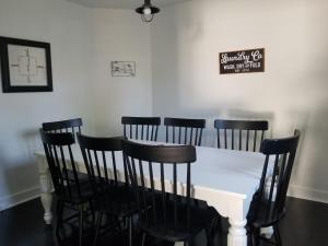 a white table with black chairs and a sign on the wall at Charlevoix House in Charlevoix