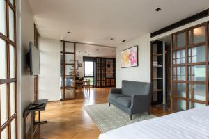 ein Schlafzimmer mit einem Bett, einem Stuhl und einem TV in der Unterkunft Sanae' Hotel Nimman in Chiang Mai