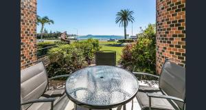 a table and chairs on a patio with a view of the ocean at Shandelle Apartments in Alexandra Headland