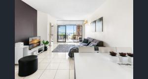 a living room with a couch and a tv at Shandelle Apartments in Alexandra Headland