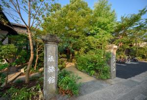 a stone pillar with writing on it next to trees at Yufuin Iyotomi in Yufuin