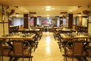 un ristorante con tavoli e sedie in una stanza di Hotel Maharana Inn Chembur a Mumbai