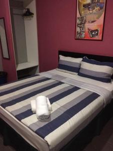 a bed with blue and white striped sheets and pillows at Metroinn Hotel in Arau