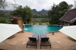 a view of a swimming pool with two chairs next to it at Shangri-Lao Resort in Luang Prabang