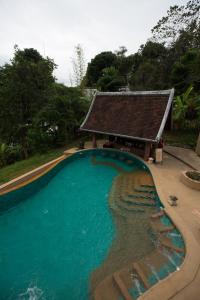 a swimming pool with a building in the background at Shangri-Lao Resort in Luang Prabang