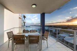 a dining room with a table and chairs on a balcony at Pumicestone Blue in Caloundra