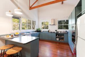 a kitchen with blue cabinets and wooden floors and windows at Jetty House in Coffs Harbour