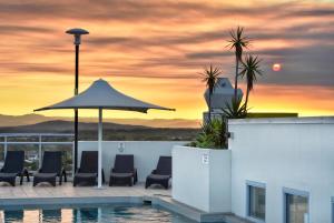 a pool with chairs and an umbrella and a sunset at Pumicestone Blue in Caloundra