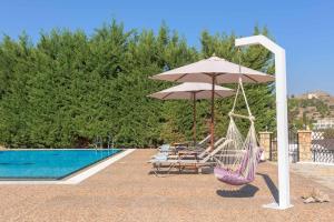 a hammock and an umbrella next to a swimming pool at Villa Krini Eleni in vlicha