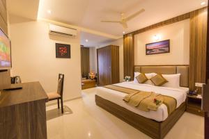 a bedroom with a bed and a desk in a room at Grand Plaza Suites in Kozhikode