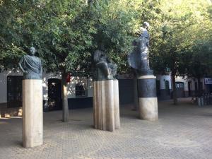 dos estatuas de personas sentadas sobre postes en APARTAMENTOS HÉRCULES SEVILLa, en Sevilla