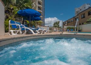 a swimming pool with chairs and an umbrella at Boulevard North Holiday Apartments in Gold Coast