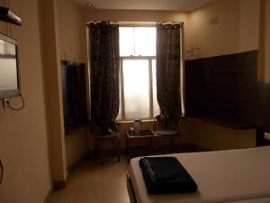 a bedroom with a bed and a window with curtains at Budget Stay in the City Center in Rishīkesh