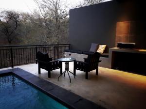 a patio with a table and chairs next to a pool at Ochre House in Marloth Park