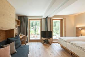 a bedroom with a bed and a tv and a couch at Hotel Albris in Pontresina