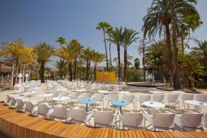a group of tables and chairs and palm trees at Abora Continental by Lopesan Hotels in Playa del Ingles