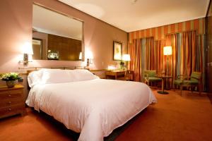 a bedroom with a large white bed and a mirror at Hotel Palafox in Zaragoza