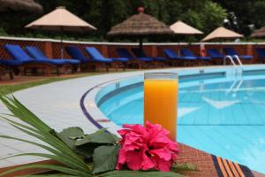 a glass of orange juice sitting on a table next to a pool at Constellation Apartments in Kampala