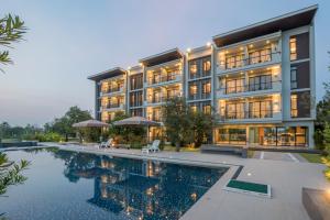 an exterior view of a building with a swimming pool at Green Ville Laguna Hotel in Sung Noen