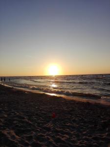 una puesta de sol en una playa con el océano en Agroturystyka Cold Sea en Sztutowo