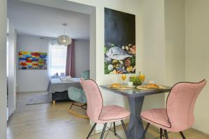 a dining room with a table and pink chairs at D&A Amphitheatre Apartments with free parking in Pula