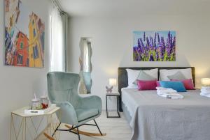 a bedroom with a bed and a blue chair at D&A Amphitheatre Apartments with free parking in Pula
