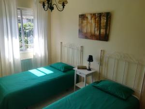 Dos camas en un dormitorio con sábanas verdes y una mesa. en La Peñita by #cherrygredos, en El Arenal 22 fotos más