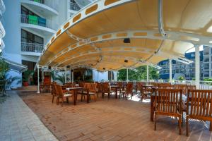 a restaurant with tables and chairs under a large umbrella at Hotel Erma in Golden Sands