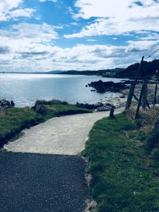 a gravel road next to a body of water at Foyleview Cottage, Moville in Moville