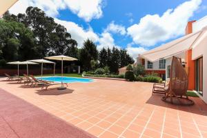 un patio con sedie, ombrelloni e piscina di Sintra Rural Home - Cerrado da Serra a Sintra