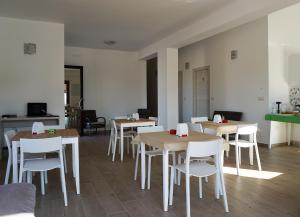 une salle à manger avec des tables et des chaises blanches dans l'établissement Il Sogno di Calipso, à Amendolara
