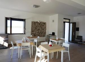 une salle à manger avec des tables en bois et des chaises blanches dans l'établissement Il Sogno di Calipso, à Amendolara