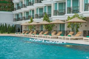 una piscina frente a un hotel con sillas y sombrillas en LK Emerald Beach - SHA Extra Plus en Pattaya North