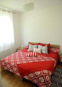 a bed with a red blanket and pillows on it at Apartment Sarajka Center in Sarajevo