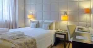 a hotel room with a bed and a chair and a desk at Your Hotel & Spa Alcobaça in Alcobaça