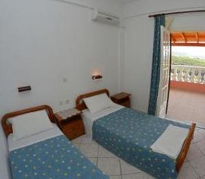 a bedroom with two twin beds and a balcony at Villa Leonidas in Agios Stefanos