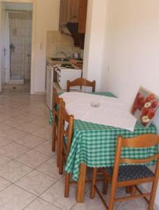 een keuken met een tafel met een groene en witte tafelkleed bij Villa Leonidas in Agios Stefanos