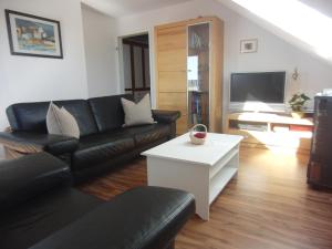 a living room with a black leather couch and a white table at Ferienwohnung Weinklang in Volkach