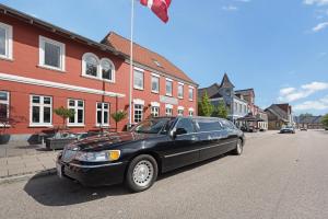 uma limusina preta estacionada ao lado de uma rua em Hotel Jernbanegade em Kibæk