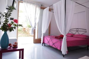 a bedroom with a pink bed with a canopy at B&B Yatabui in Patù