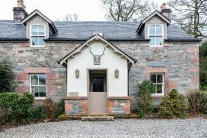 une ancienne maison en pierre avec une porte d'entrée. dans l'établissement Luss Cottages at Loch Lomond Arms Hotel, à Luss