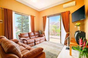 a living room with a leather couch and a television at Villa Alessandra Seminyak By Bali Asia Villa in Seminyak