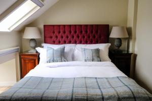 une chambre avec un grand lit avec une tête de lit rouge dans l'établissement Luss Cottages at Loch Lomond Arms Hotel, à Luss