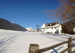 une clôture devant une maison dans la neige dans l'établissement Ansitz Goller, à Rasun di Sopra