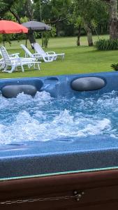 a swimming pool with two chairs and a table and umbrella at 'La Maison Catalpa' French Farmhouse with Pool & Jaccuzi in Saint-Privat-des-Prés